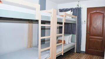 A room with bunk beds, a wooden door, and a curtain.