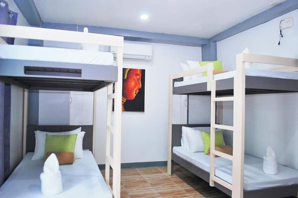 Une chambre avec des lits superposés, un tableau au mur et un luminaire au plafond.