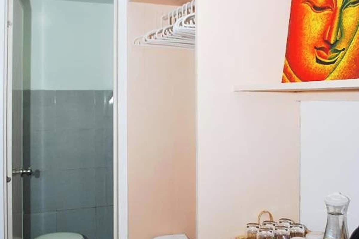 Une salle de bain avec une douche à parois de verre, des toilettes et une étagère contenant des serviettes et des articles de toilette.