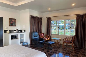 Ein Hotelzimmer mit Bett, Schreibtisch mit Wasserkocher, Stuhl, kleinem Tisch und Blick ins Freie.