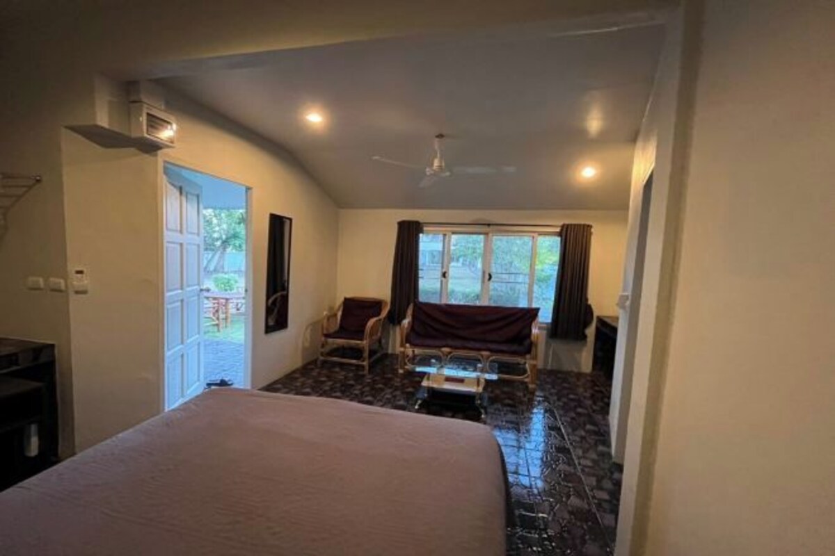 Une chambre à coucher avec un lit, un ventilateur de plafond, une fenêtre avec des rideaux et une vue sur l’extérieur.