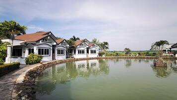A series of white buildings with red roofs and a calm water body in the foreground.
