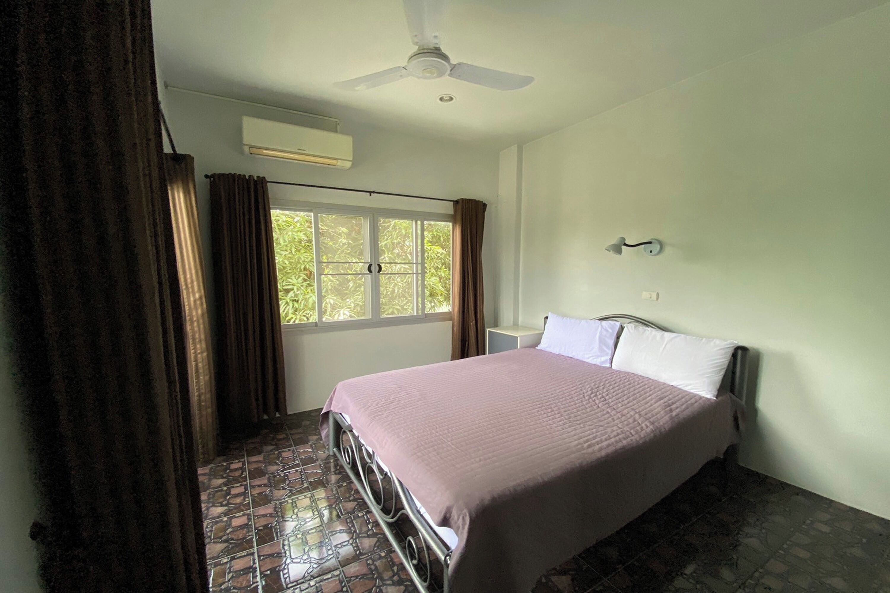 A bedroom with a bed, a ceiling fan, a window with curtains, and a tiled floor.