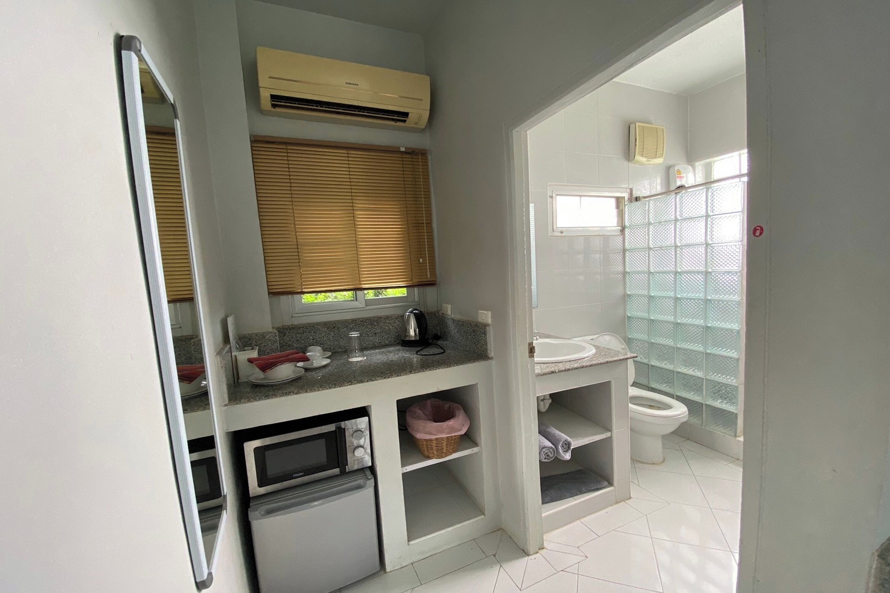 A compact bathroom with a toilet, sink, and a small refrigerator.