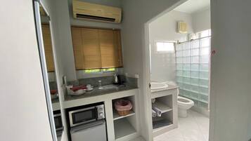 A compact bathroom with a toilet, sink, and a small refrigerator.