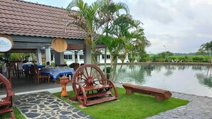 Un restaurant doté d’une terrasse, d’un bassin et d’un bâtiment dont le toit est recouvert de tuiles.