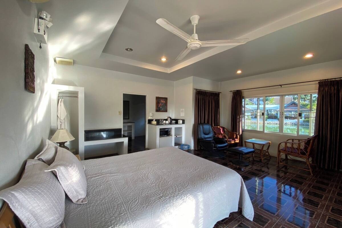 Une chambre d’hôtel avec un grand lit, un bureau, une chaise, une table à manger et une vue sur l’extérieur.