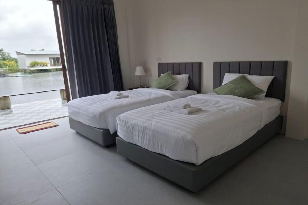 A hotel room with two beds, a view of a body of water, and a balcony.