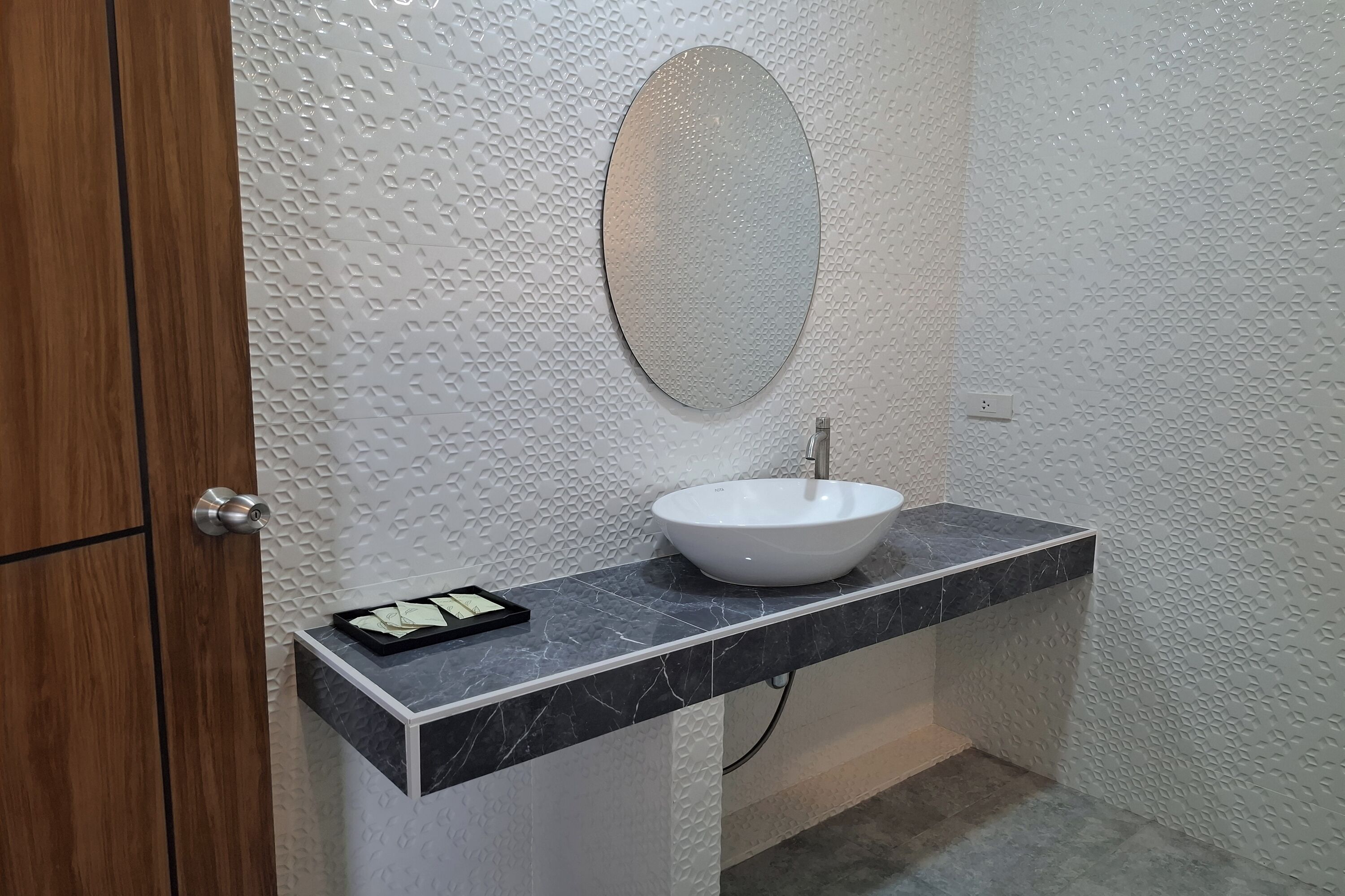A bathroom with a white sink, a mirror, and a wooden door.