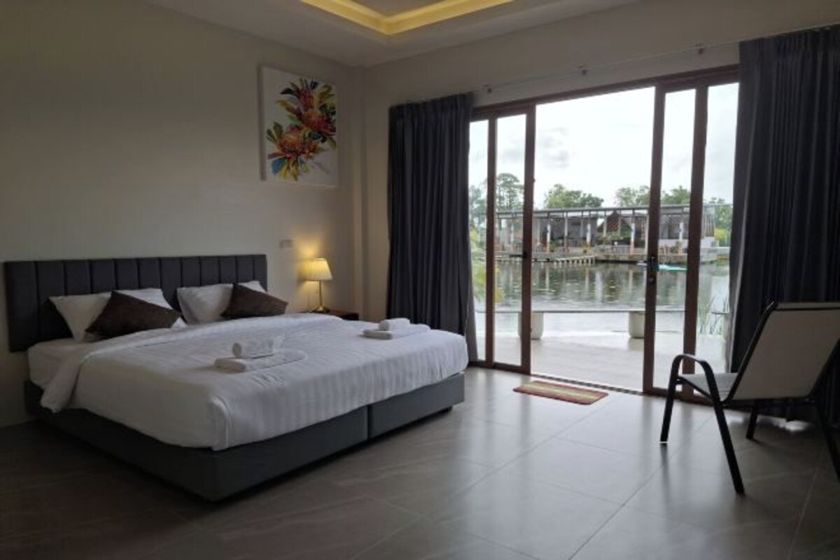 A modern hotel room with a large bed, a balcony with a view, and a chair.