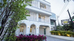 A multi-story building with balconies, arched windows, and a sign indicating it is a number 4 apartment building. - Number 4 Phuket (Rawai)