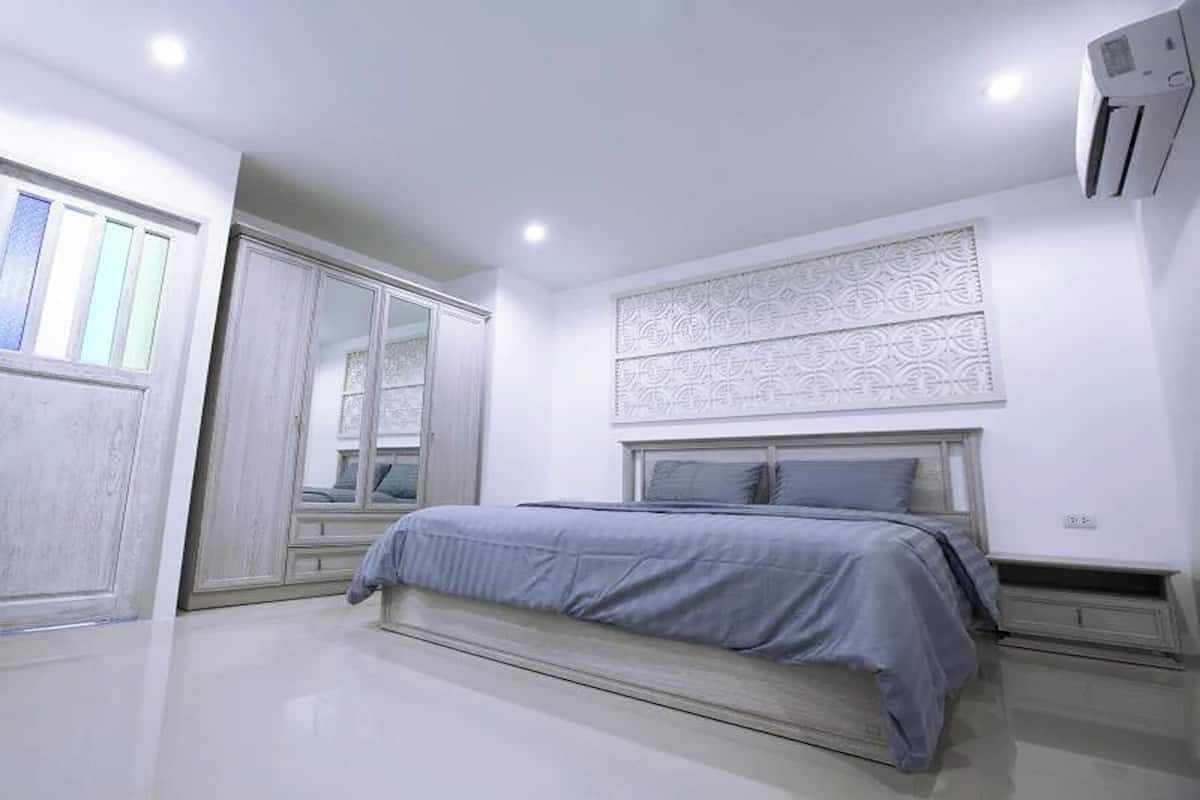 A bedroom with a bed, a wardrobe, and a decorative wall panel.
