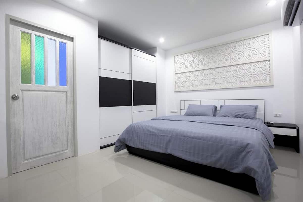 A bedroom with a bed, a wardrobe, and a decorative wall panel.