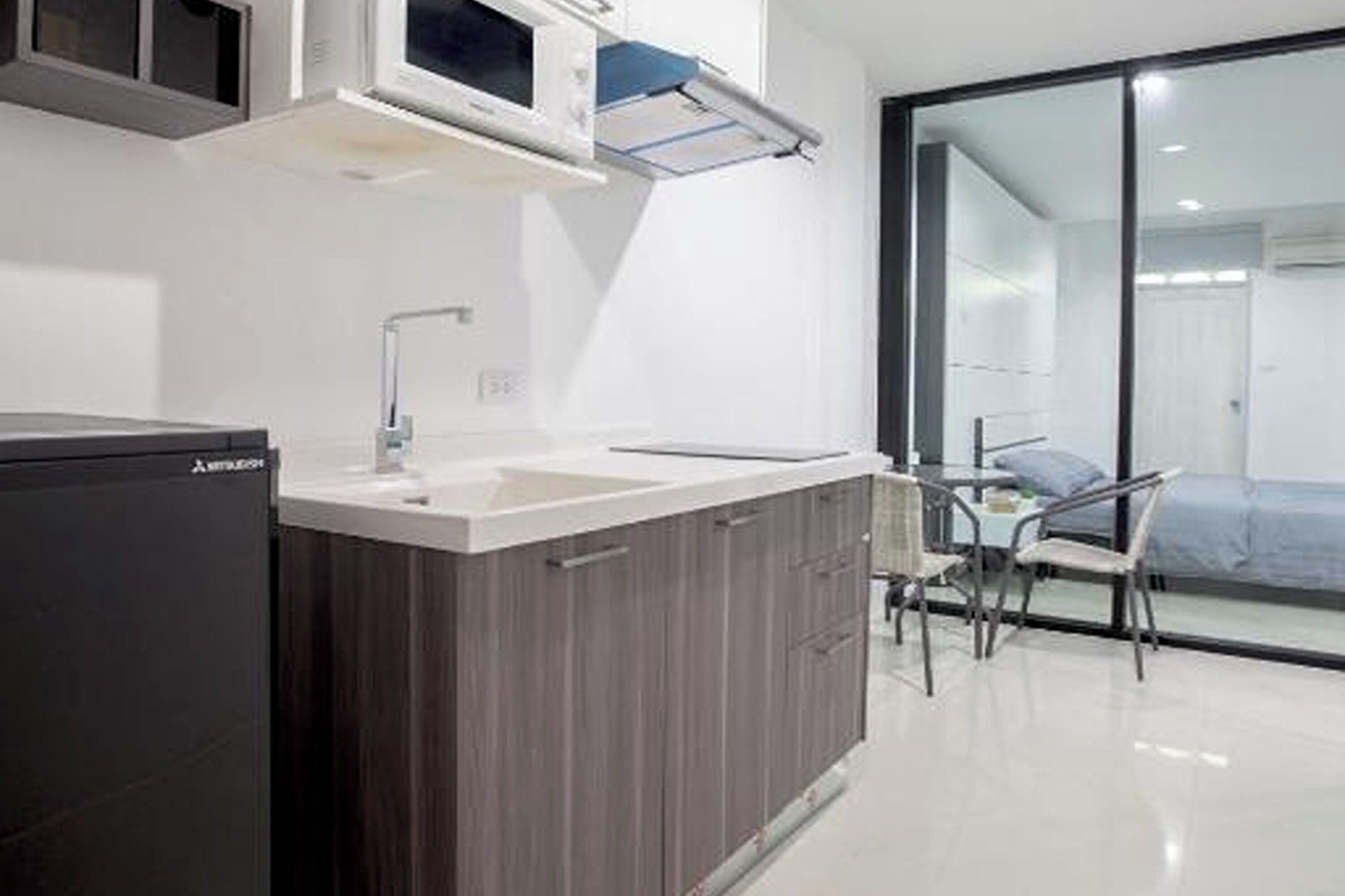 A modern kitchen with a built-in refrigerator, a sink, and a window overlooking a balcony.