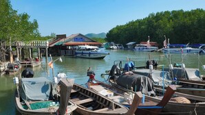 A dock with several boats, a wooden structure, and a building with a sign. - Snooze Inn Phuket (Pa Klok)