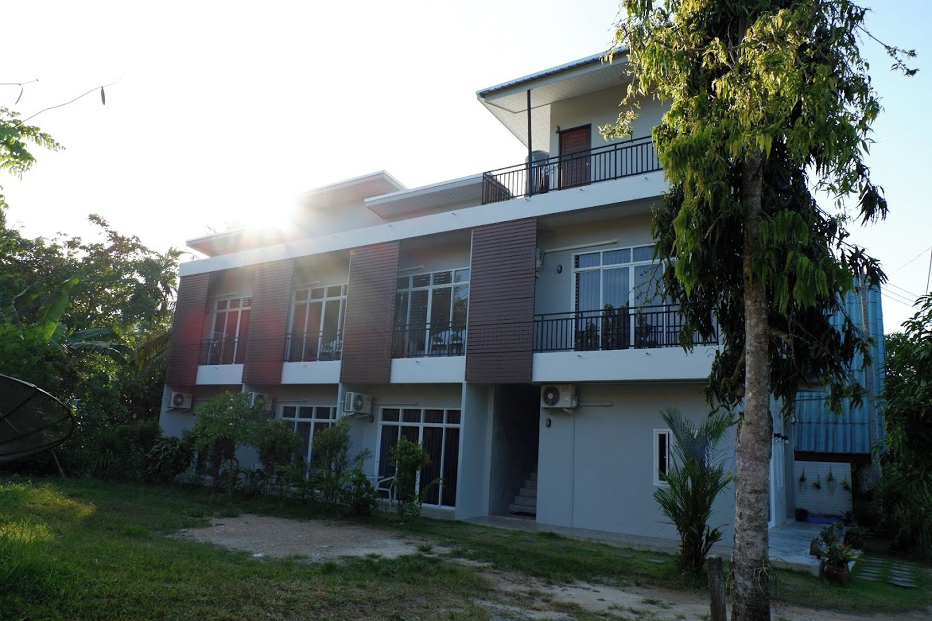 A multi-story residential building with balconies, large windows, and a well-maintained garden.