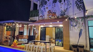 Una villa moderna con zona pranzo, posti a sedere all'esterno e un murale sulla parete esterna.