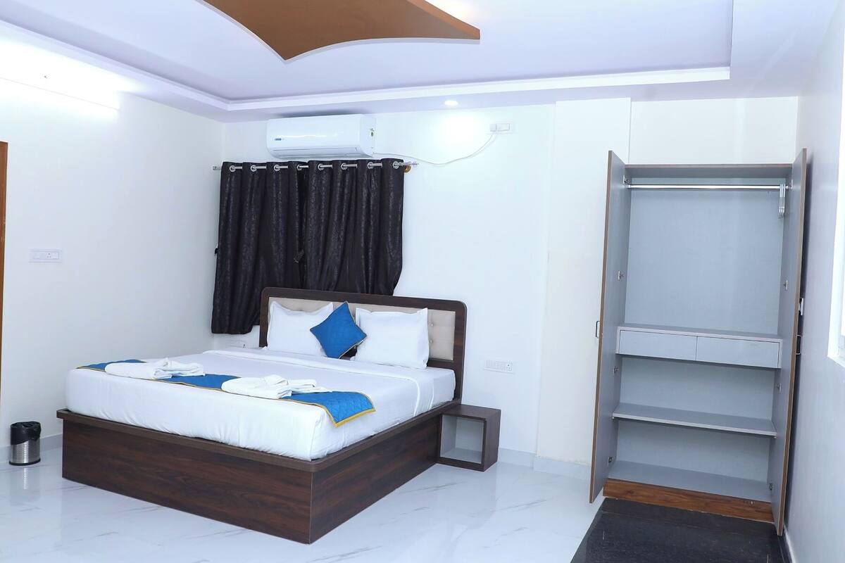 A modern hotel room with a neatly made bed, a built-in wardrobe, and a small bedside table.