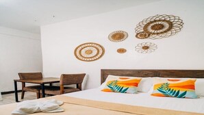 Een hotelkamer met een bed, twee stoelen, een tafel en wanddecoratie.