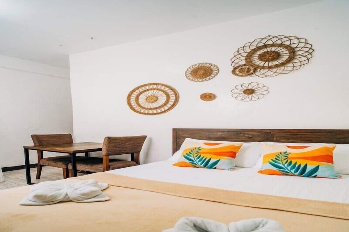 Habitación de hotel con cama, dos sillones, una mesa y decoración en las paredes.