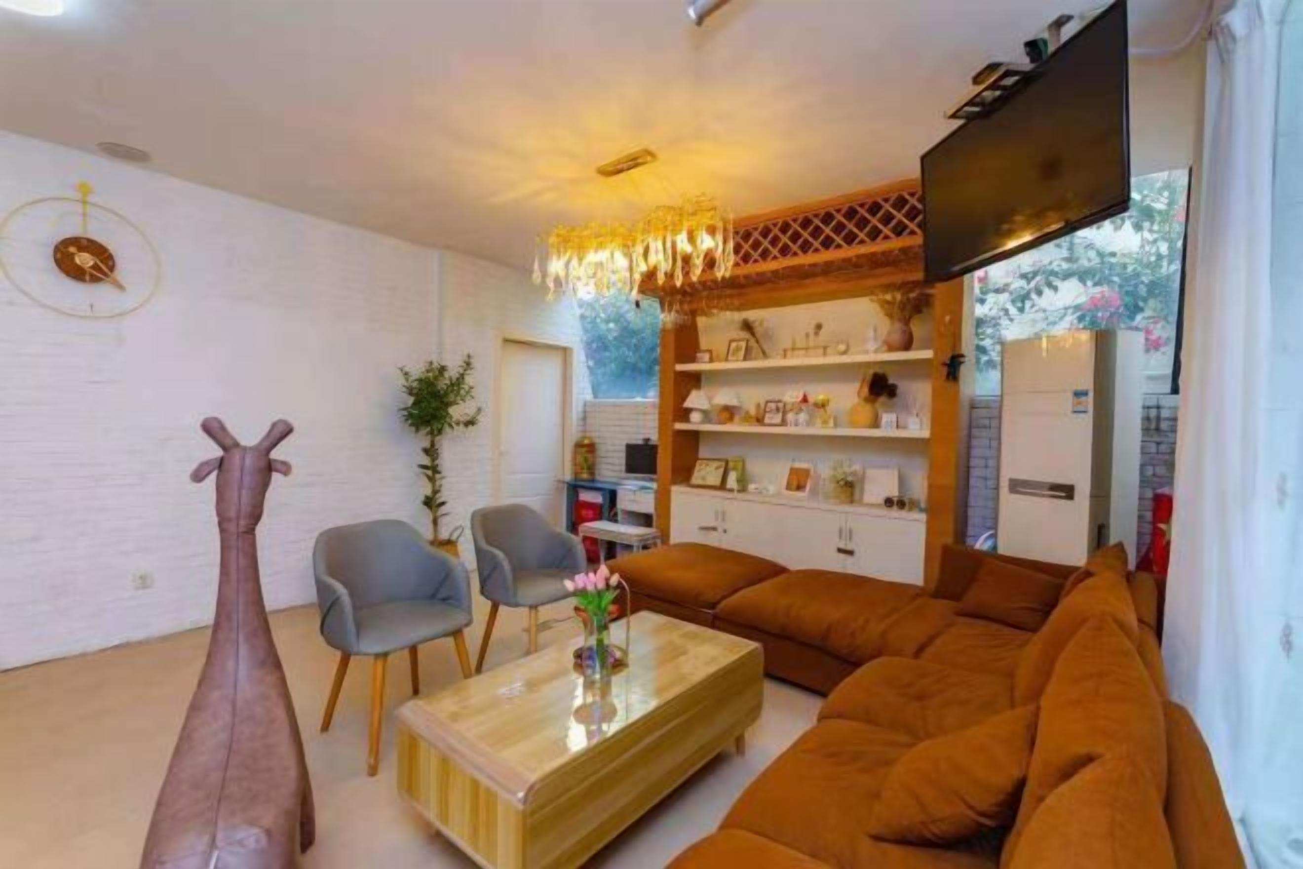 A modern living room with a sofa, chairs, a coffee table, a TV, and a decorative giraffe sculpture.