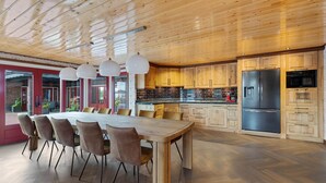 A modern kitchen with wooden cabinets, a large dining table, and pendant lights. - Detached Home in Friesland by Canal (Jistrum / Skûlenboarch)