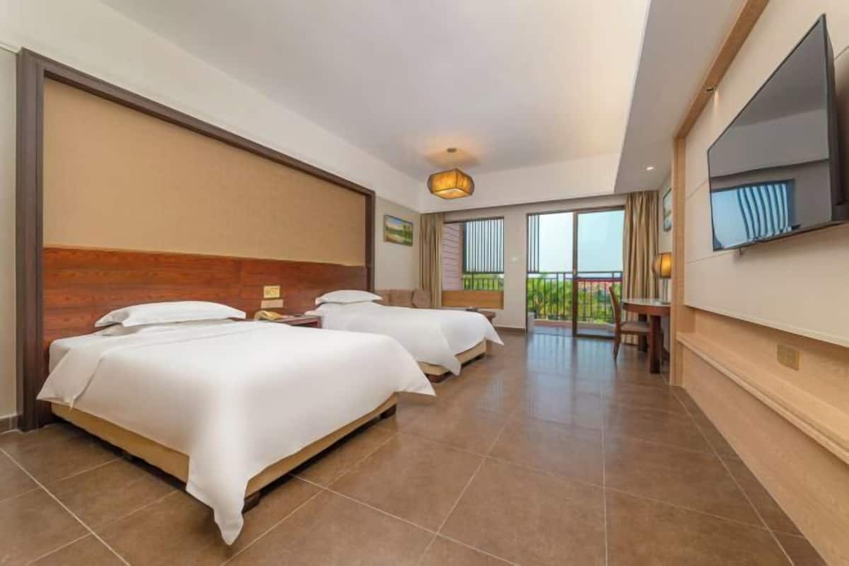 Ein Hotelzimmer mit zwei Betten, einem Fernseher und einem Balkon mit Blick.