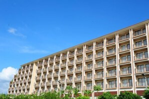 A multi-story hotel with a uniform facade, balconies on each floor, and a clear blue sky in the background. - Dreamland Resort Hotel (Taishan)