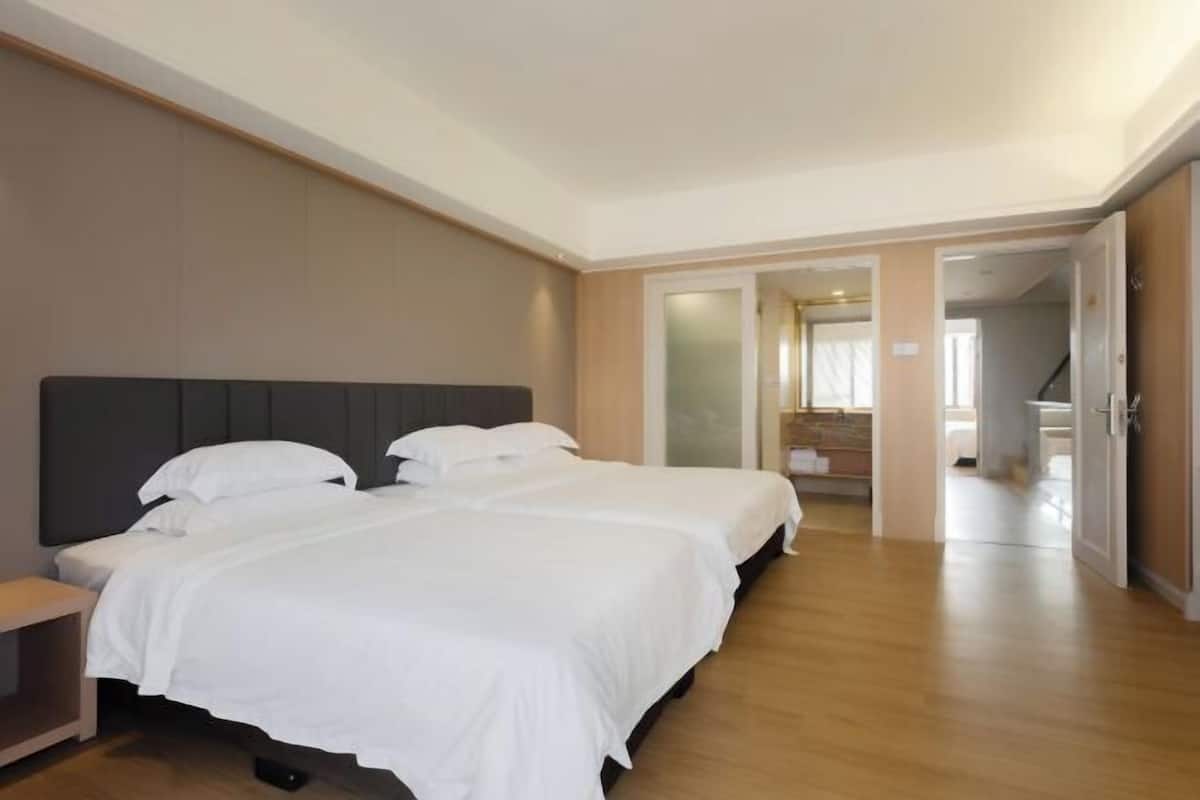Ein Hotelzimmer mit zwei Betten, Holzboden und Blick auf den Flur.