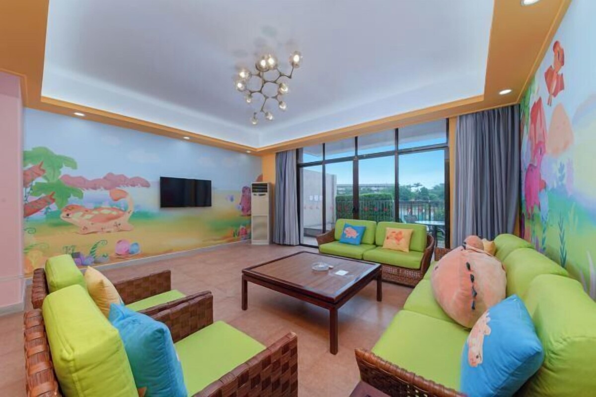 A spacious living room with green sofas, a wooden coffee table, and a mural on the wall.