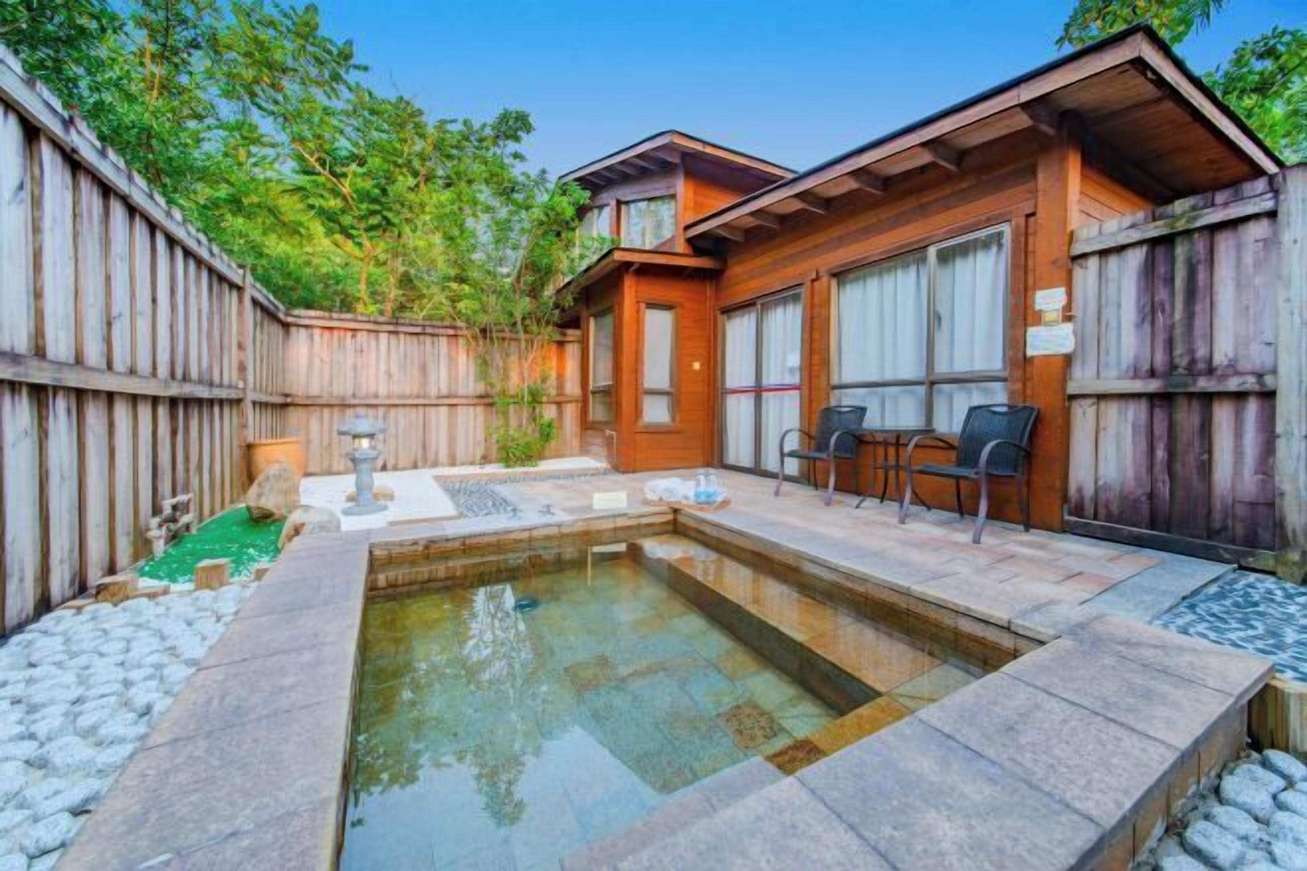 Una cabaña de madera con jacuzzi, un sendero de piedra y una zona de estar al aire libre.