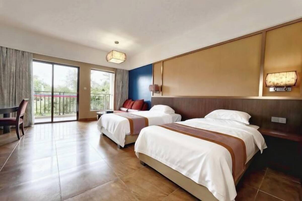 Ein Hotelzimmer mit zwei Betten, einem Balkon und einem Essbereich.