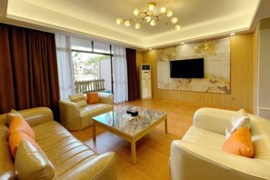 A living room with a sofa, armchair, and coffee table. - Dreamland Resort Hotel (Taishan)