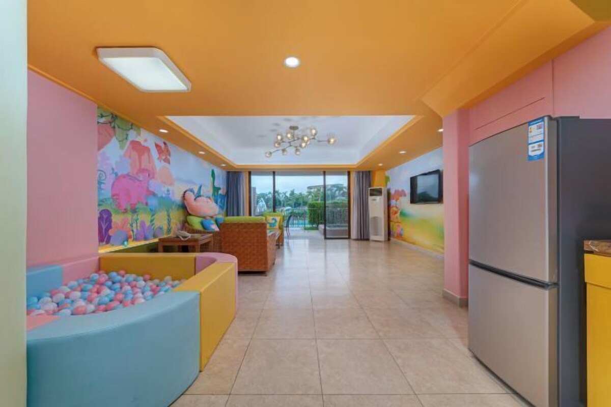 A brightly colored play area with a ball pit, seating, and a mural on the wall.