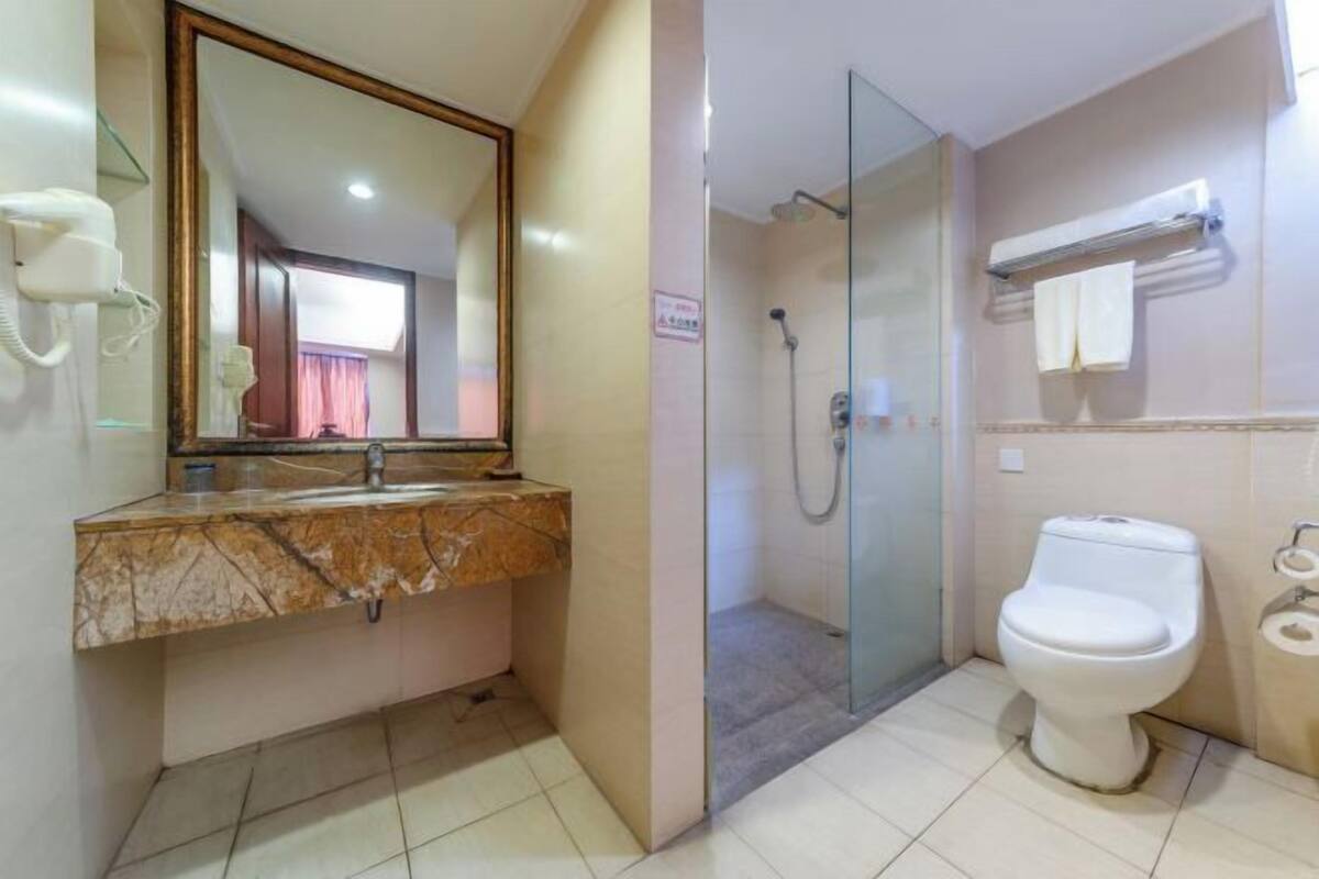 Ein Badezimmer mit Marmorwaschtisch, einer Glasdusche und einer Toilette.