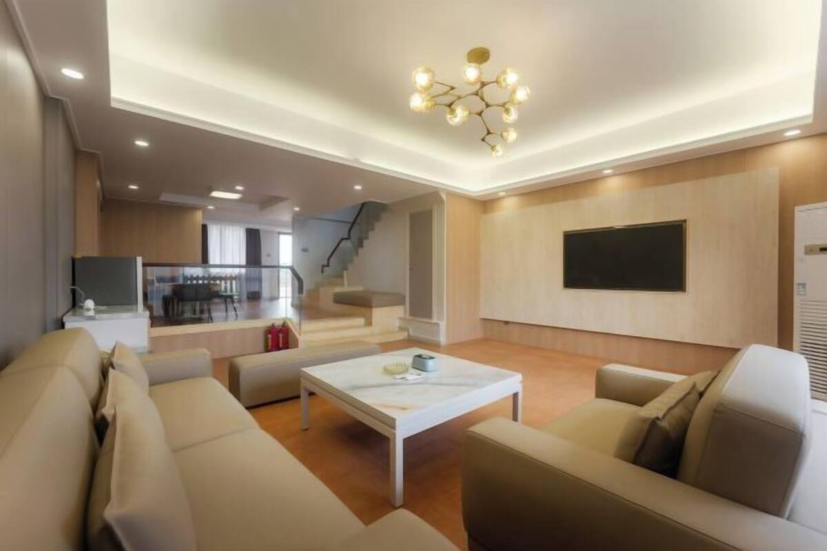 Ein modernes Wohnzimmer mit einer Sofagarnitur, einem Couchtisch und einem an der Wand montierten Fernseher.