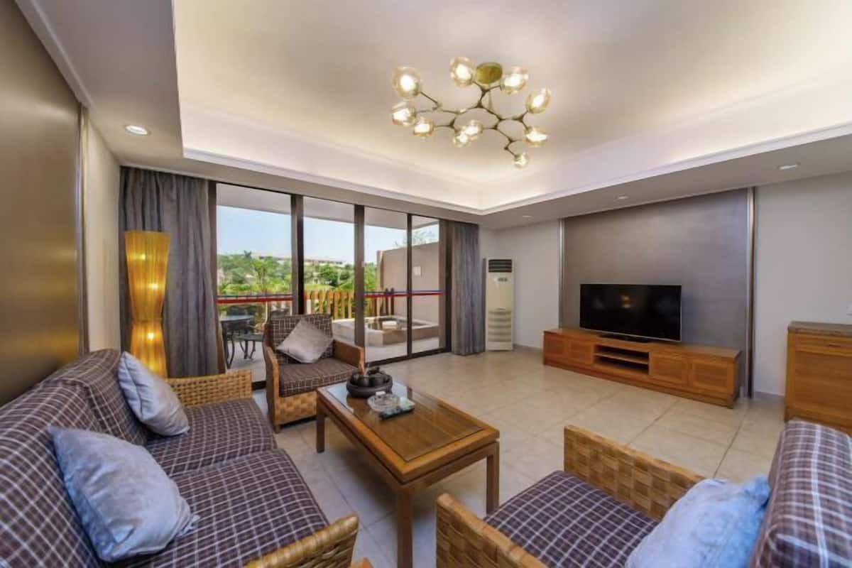Ein modernes Wohnzimmer mit einer Sofagarnitur, einem Couchtisch, einem Fernseher und einem Balkon mit Blick.