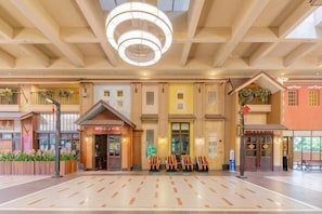 Eine großzügige Lobby mit einem offenen zentralen Bereich, verschiedenen Sitzgelegenheiten und einem modernen Deckenstil.
