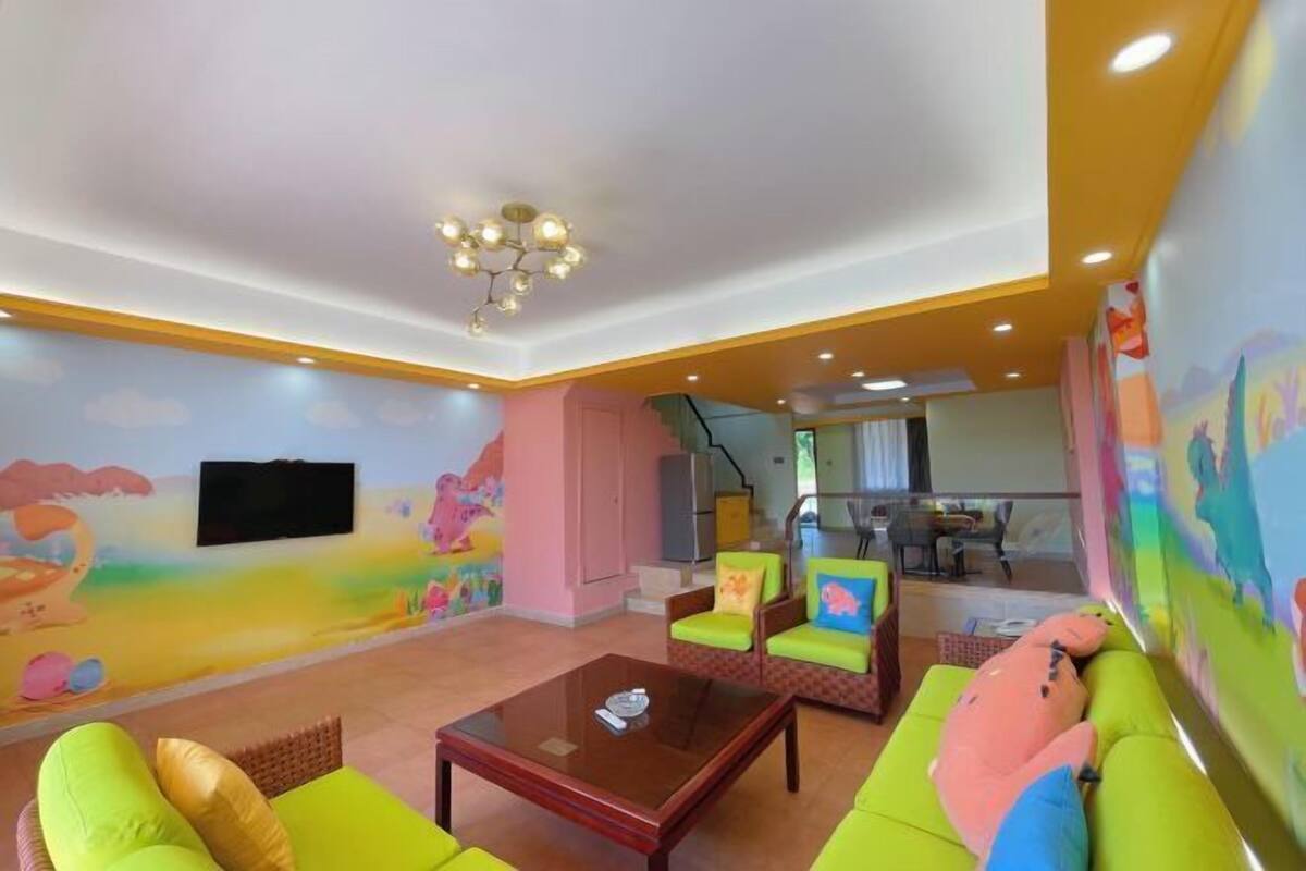 Ein Wohnzimmer mit einer Couch, Sesseln, einem Couchtisch, einem Fernseher und einem Wandgemälde.