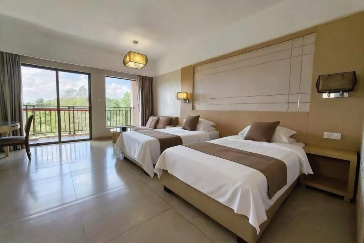 Ein Hotelzimmer mit zwei Betten, einem Balkon und einem großen Fenster.