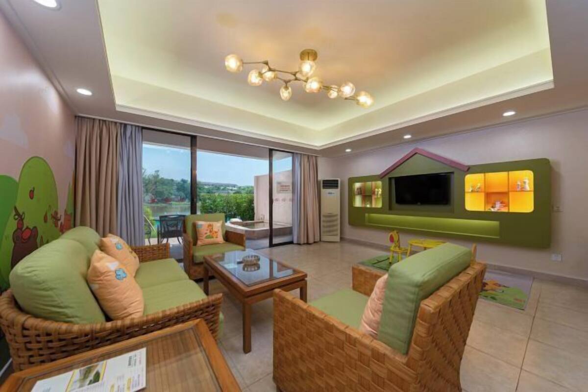 Ein modernes Wohnzimmer mit Rattanmöbeln, einem Glastisch, einem flachbildfernseher an der Wand und einem Balkon mit Blick.