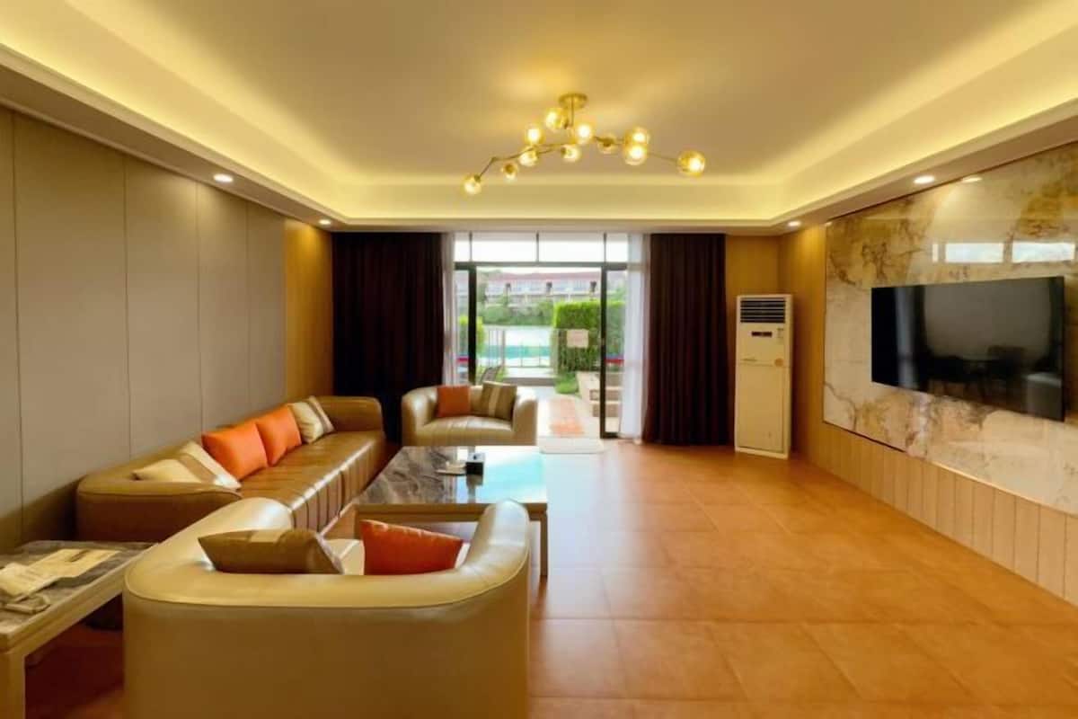 Ein modernes Wohnzimmer mit einer Sofagarnitur, einem Couchtisch und einem an der Wand montierten Fernseher.