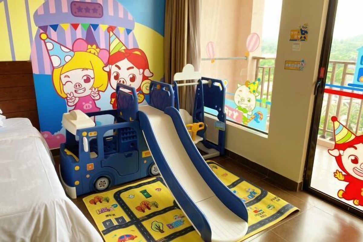 A children's play area with a slide, a toy bus, and a mat with cartoon characters.