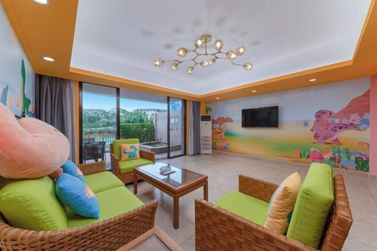 Ein Zimmer mit Korbmöbeln, einem Glastisch, einer Deckenleuchte und einem Wandgemälde.