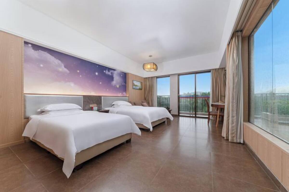 Ein Hotelzimmer mit zwei Betten, einem großen Fenster und einem Balkon.