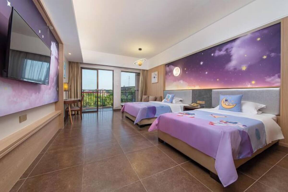 Ein Hotelzimmer mit zwei Betten, einem Fernseher, einem Balkon und einem Wandgemälde mit Sternenhimmel.