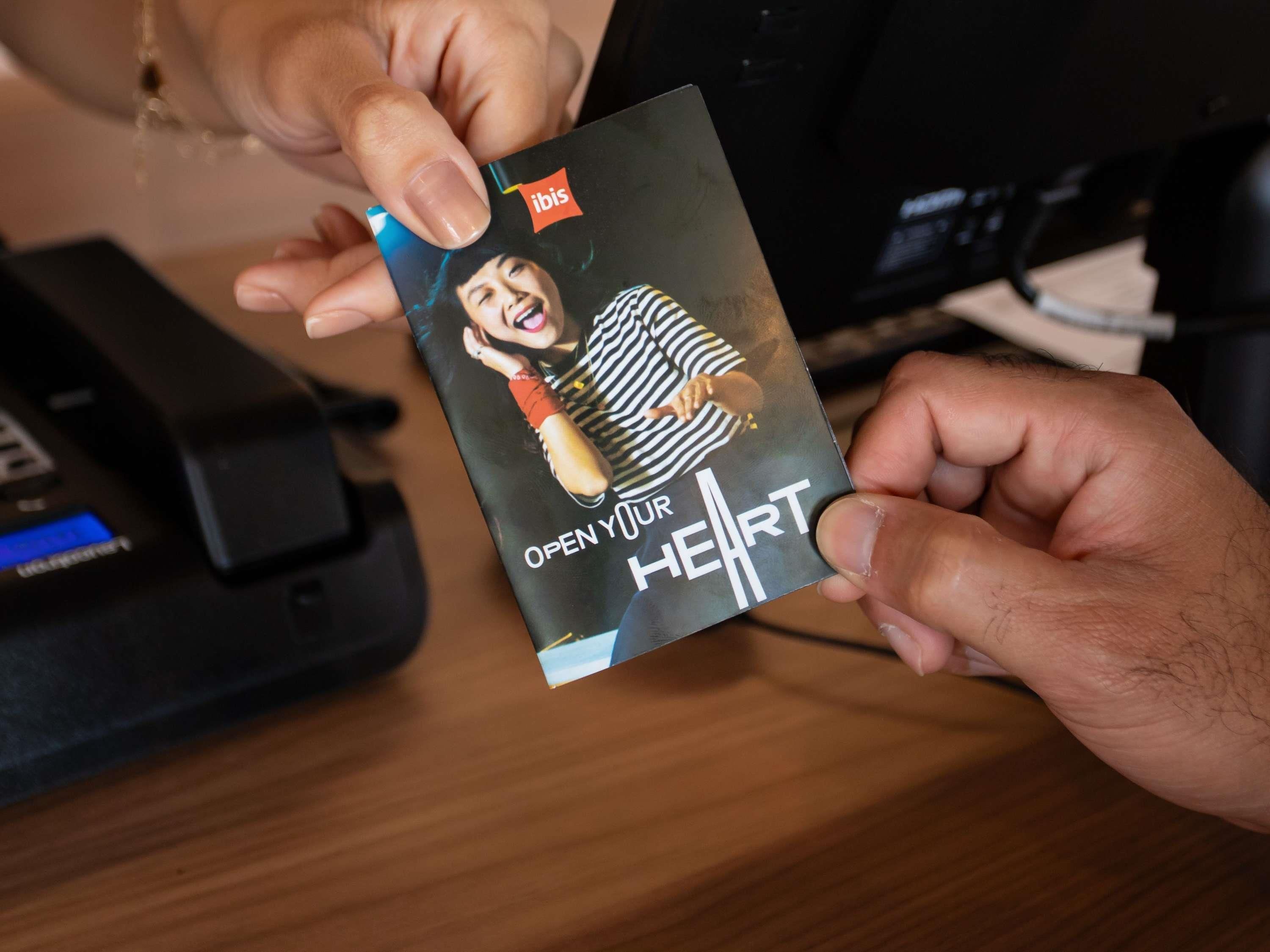 A person holding a book titled 'Open Your Heart' with a striped pattern on the cover.