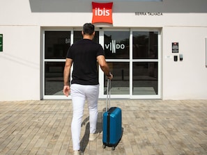 A man walking towards a building with a sign that reads 'ibis' and 'SERRA TALHADA' on the facade. - Ibis Serra Talhada (Serra Talhada)
