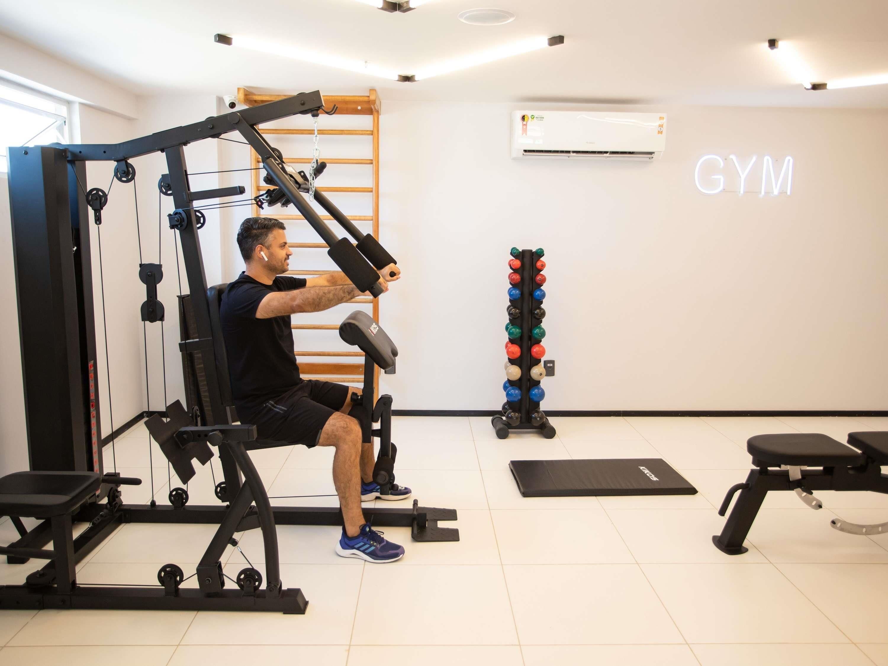 Un gimnasio con un banco de pesas, una estructura para sentadillas y un estante con mancuernas.