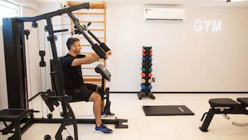 Un gimnasio con un banco de pesas, una estructura para sentadillas y un estante con mancuernas.